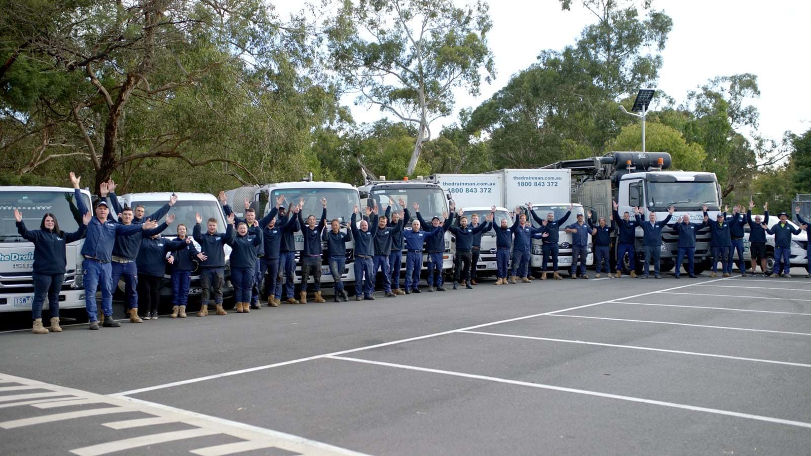 The Drain Man team waving in front of their fleet of vans and trucks